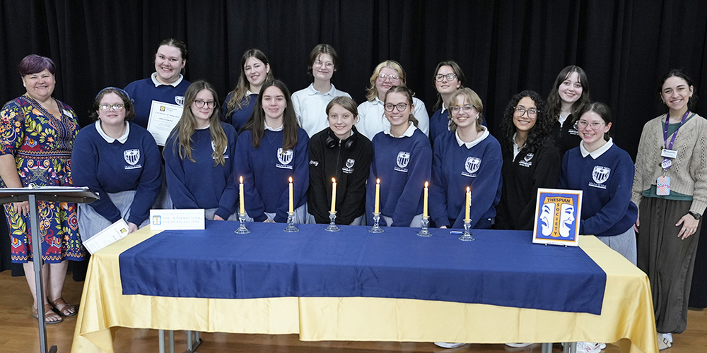 large group of students smiling at the camera with adults on either side
