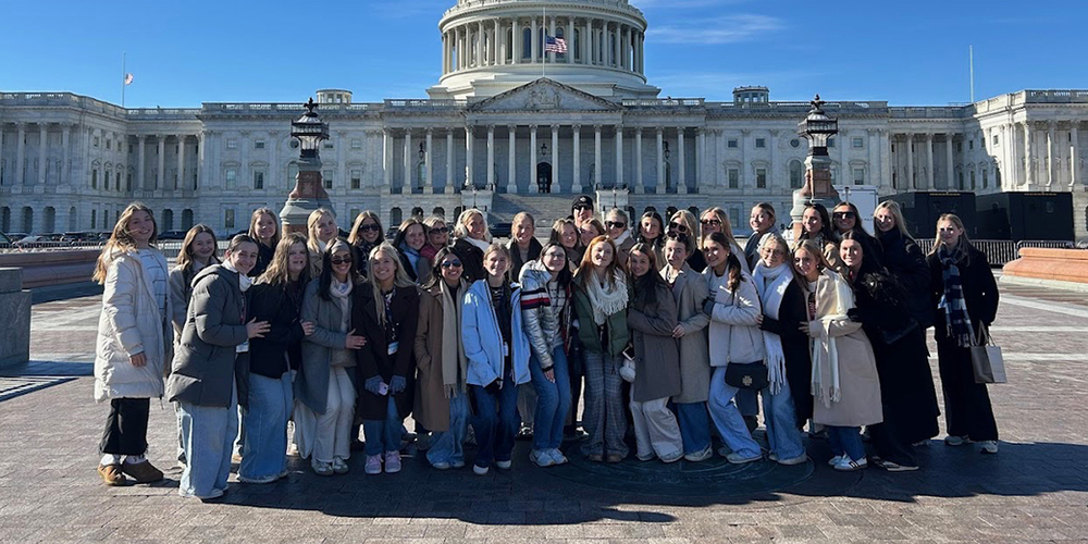 large group of students stand in front of U.S. Capitol building