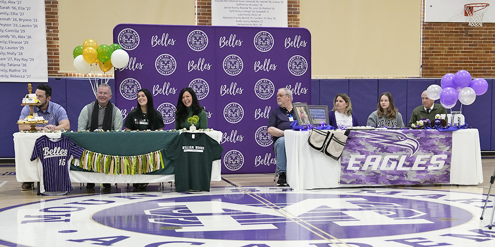 students and guests sit at two decorated tables at center of gymnasium