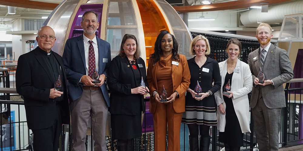 seven individuals holding awards and smiling at the camera