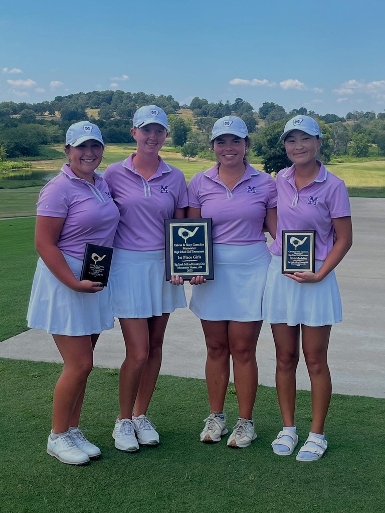 four female golfers standing on green golf course and holding award plaques