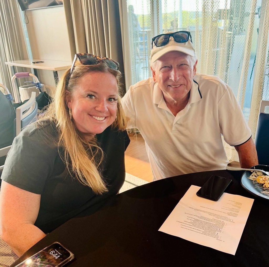 two individuals standing at table on patio and smiling at camera