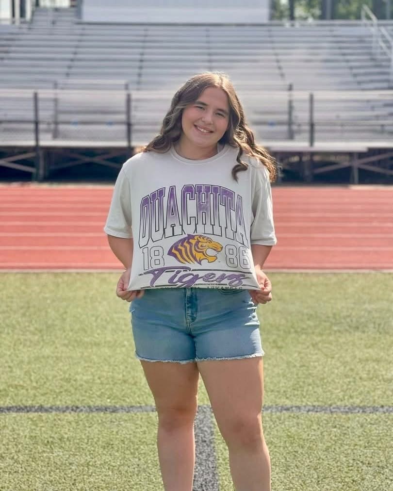 young woman standing on football field with empty bleachers in background