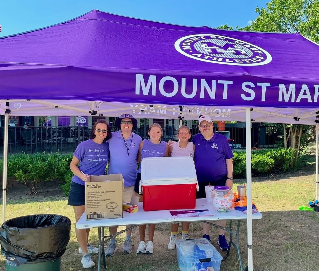 five individuals standing outside under purple tent