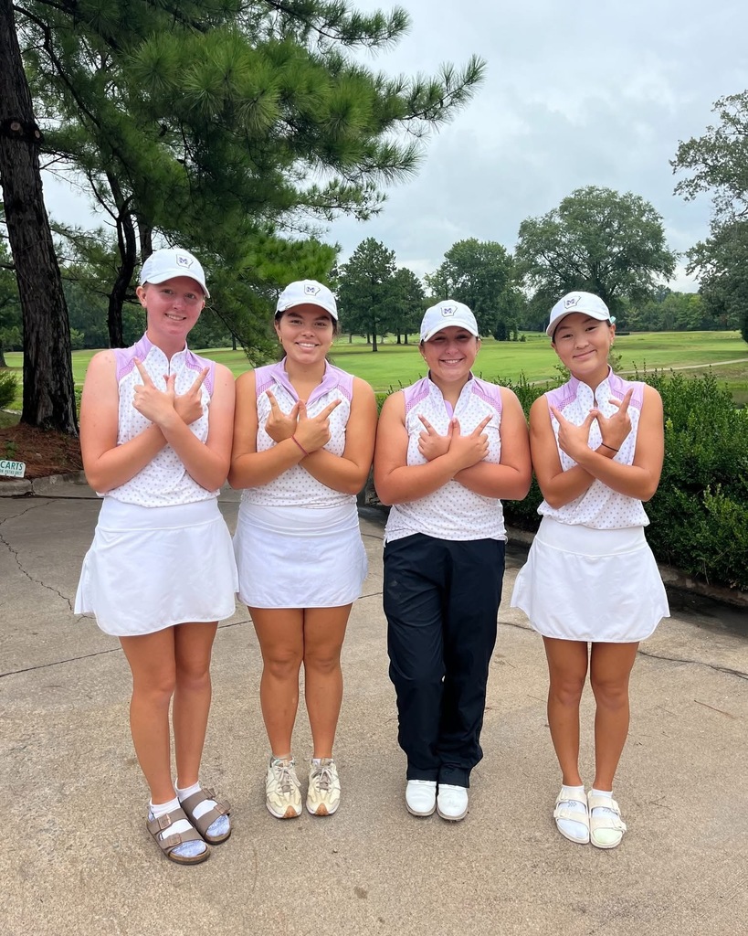 four female golfers in uniform with golf course in background