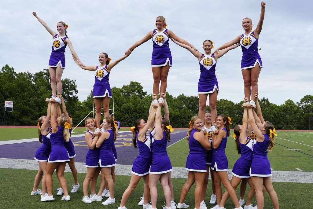 cheerleaders in white, purple and gold uniforms and in pyramid on football field