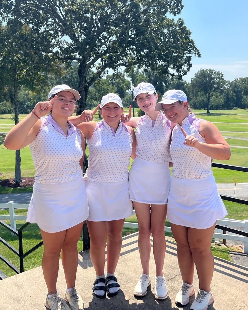four female golfers giving #1 hand gestures with golf course in background 