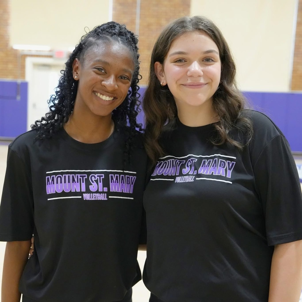 two students in black t-shirts smiling at camera