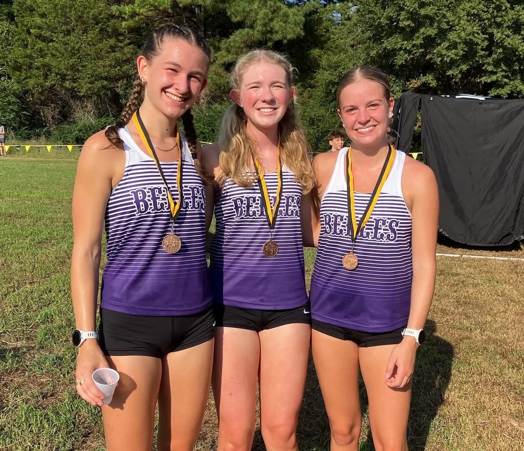 three female cross country athletes with medals around the necks