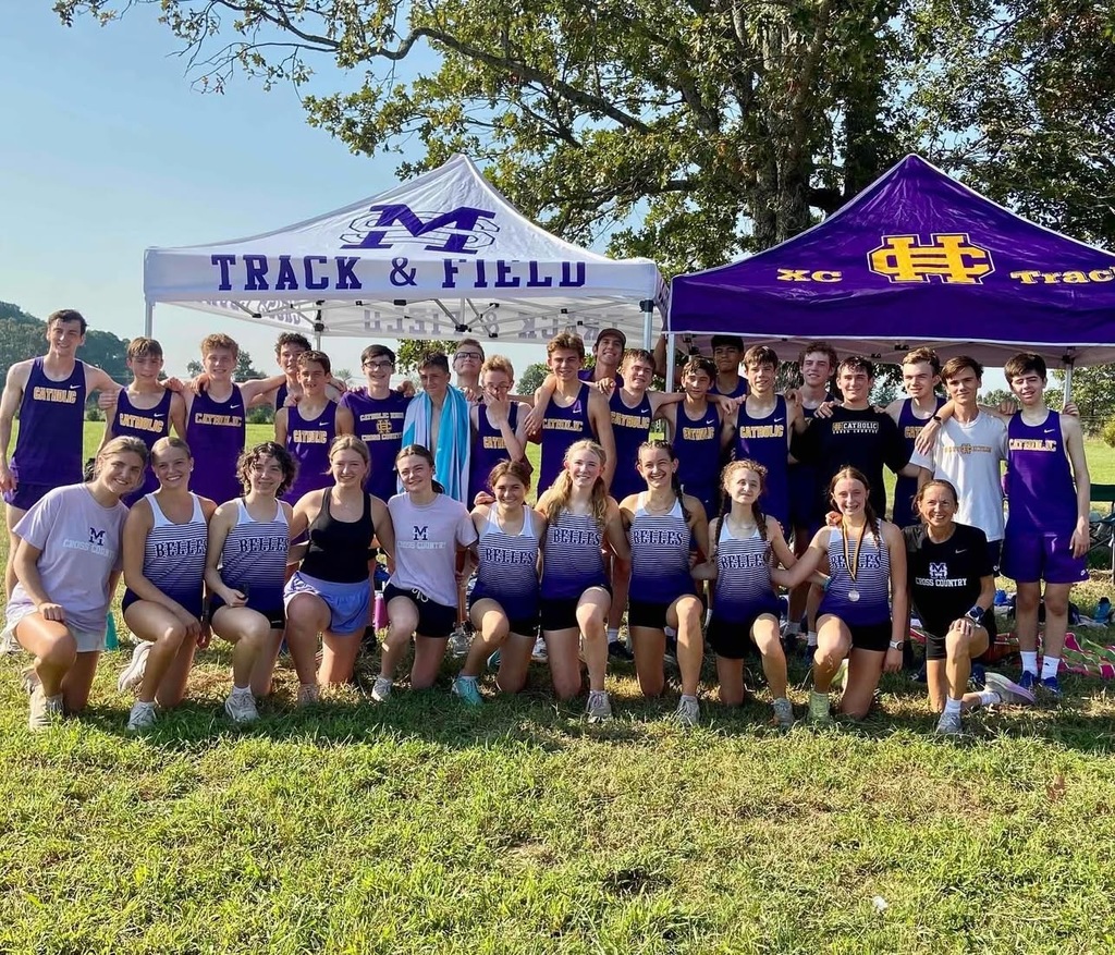large group of female and male cross country runners in front of tents on large grassy area