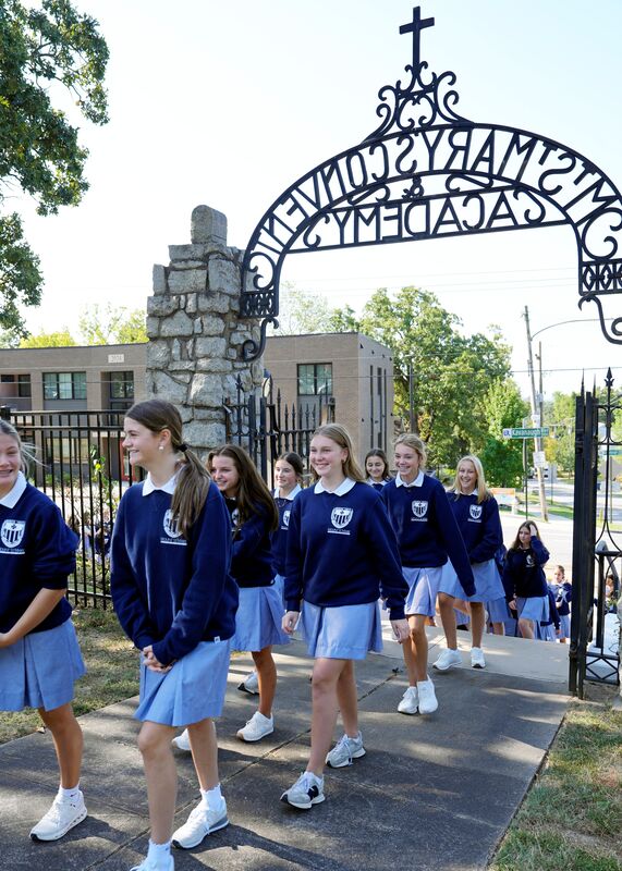 group of students walking through historic gate at entrance to school