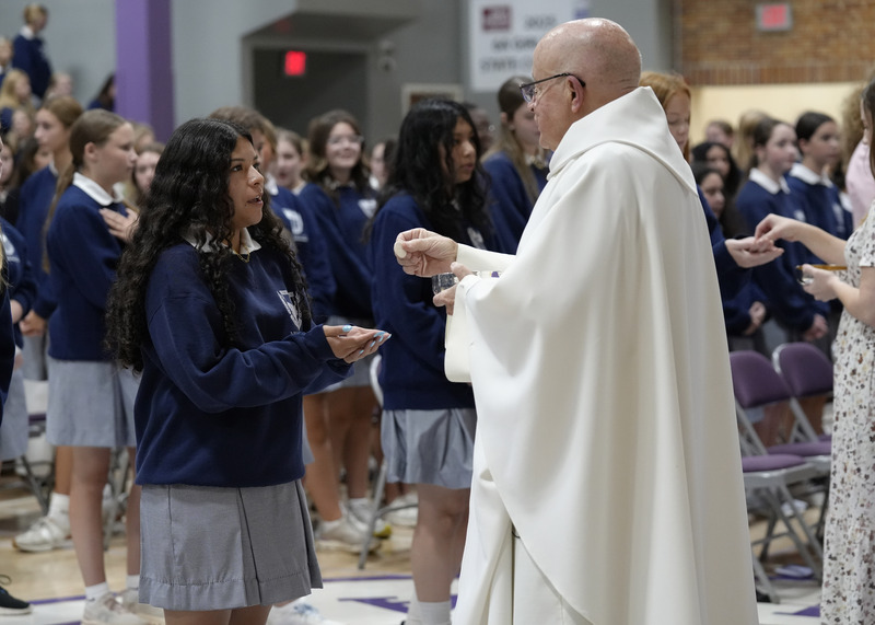 a student receiving communion from a priest