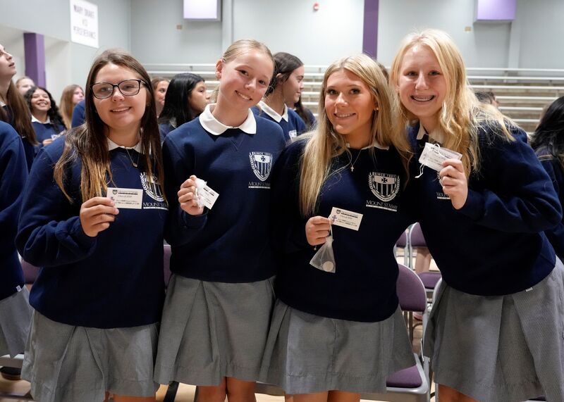 four students holding small Mercy cards