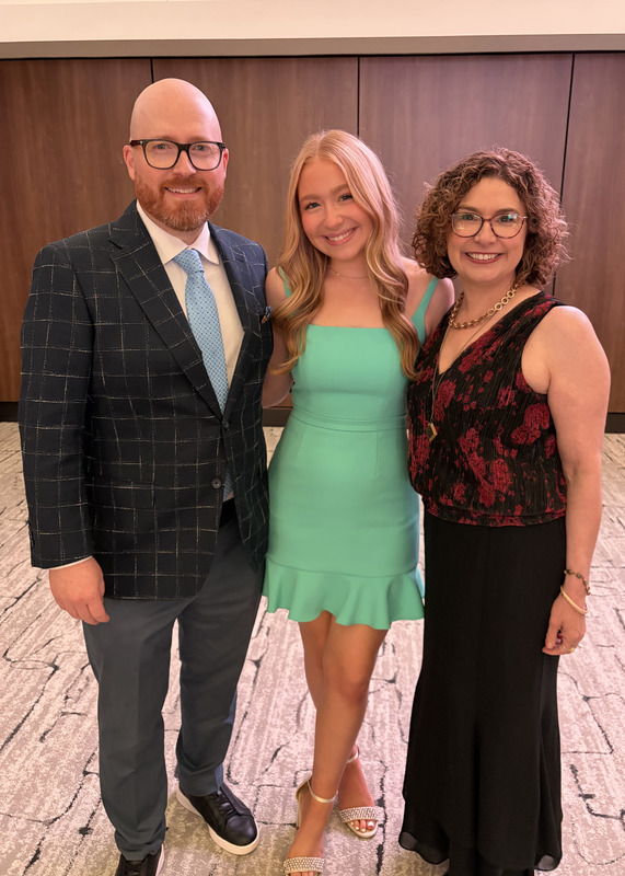 three figures standing together and smiling at the camera