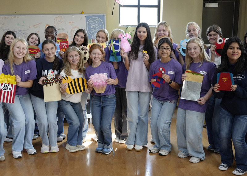 a large group of students holding handmade felt Halloween costumes for infants