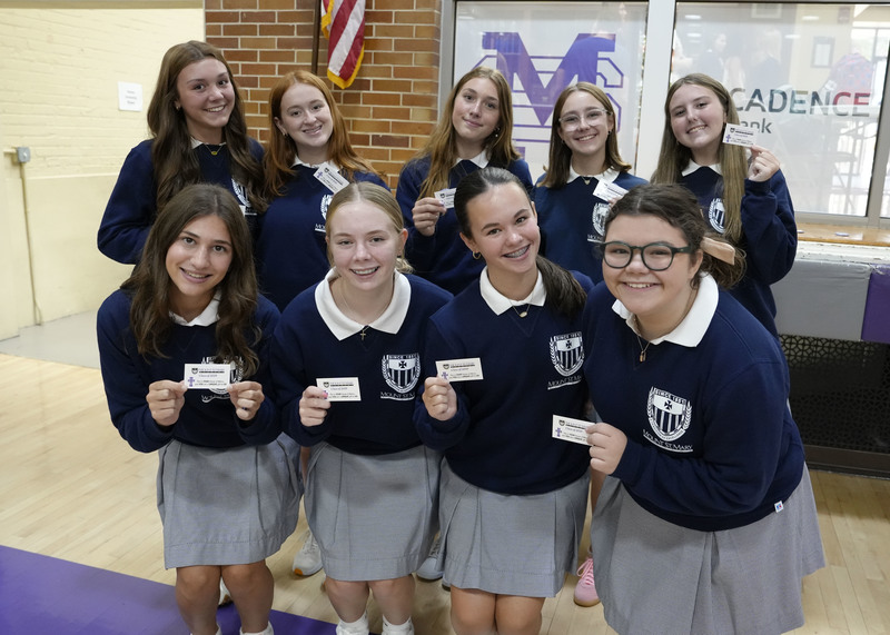 nine students holding up their Mercy Cards and smiling at the camera