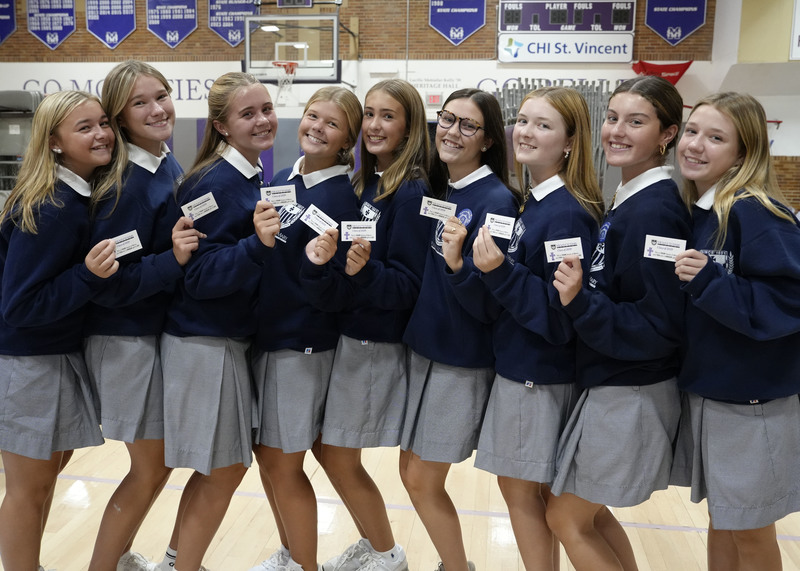 nine students holding up their Mercy Cards and smiling at the camera