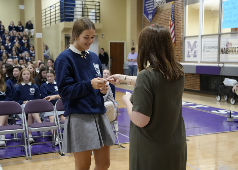 student receiving her Mercy Card from a teacher