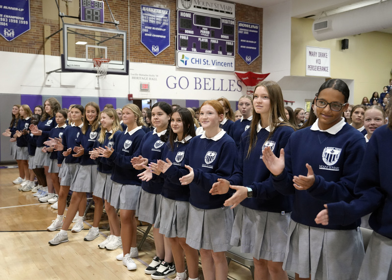 row of young women in school uniform clapping and singing during Opening School Mass