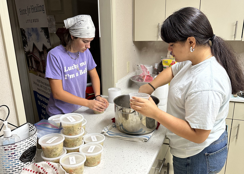 two young women preparing soup in a kitchen