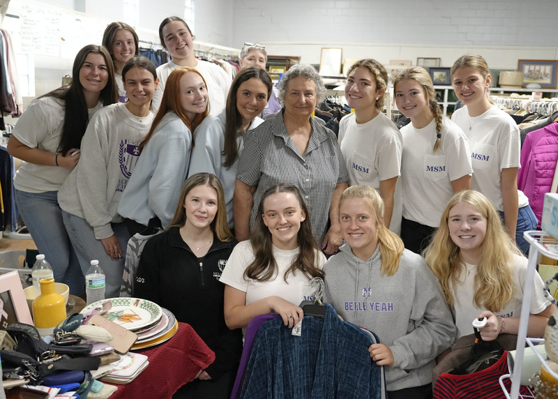 large group of young women standing in a thrift store