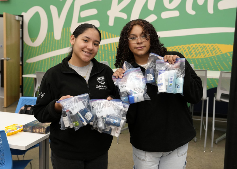 two young women holding hygiene kits