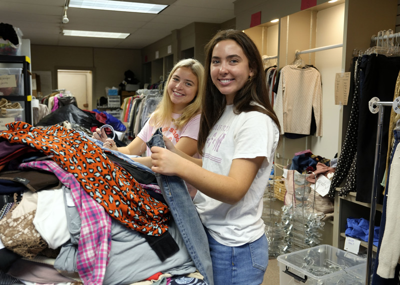 two young women sorting through clothing in a consignment store