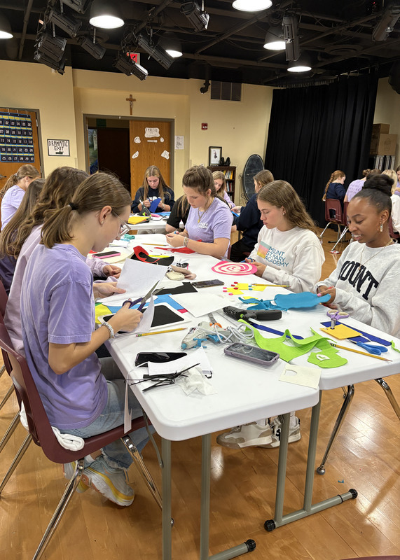 a group of young women seated around a table doing arts and crafts