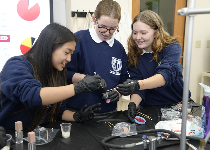 three students making lip gloss in a science lab