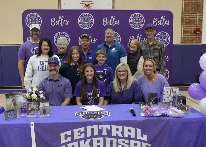 student athlete sitting at table surrounded by family