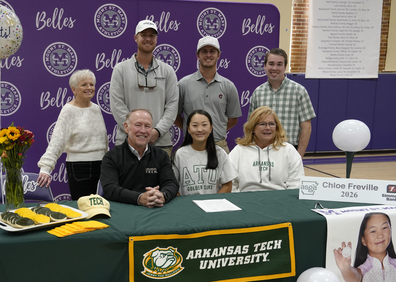 student athlete sitting at table surrounded by family