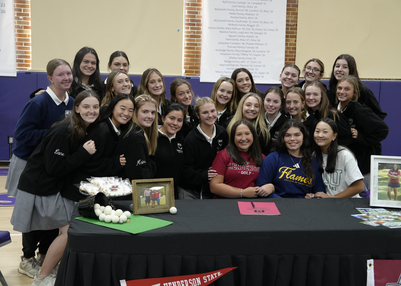 student athletes sitting at table surrounded by teammates