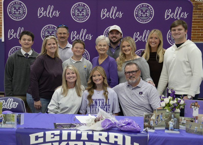 student athlete sitting at table surrounded by family