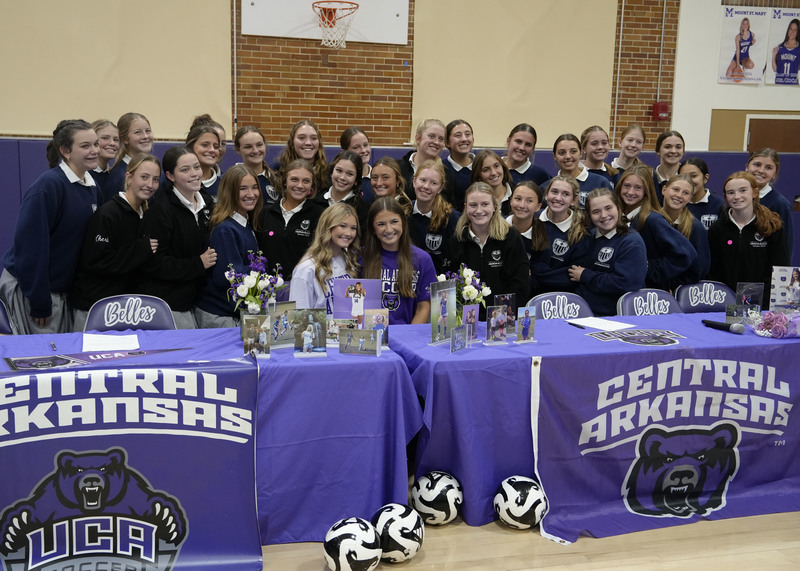 student athletes sitting at table surrounded by teammates