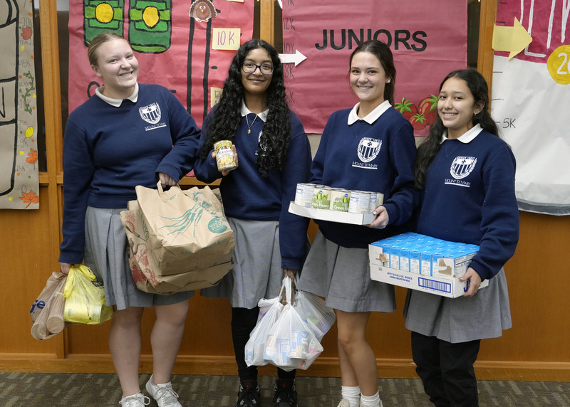four girls standing with boxes and plastic bags of canned goods