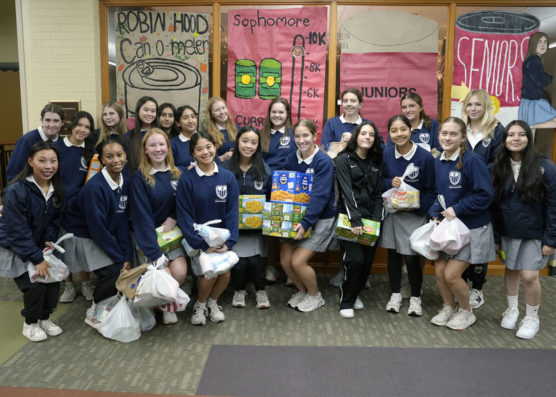 large group of girls standing with boxes and plastic bags of canned goods