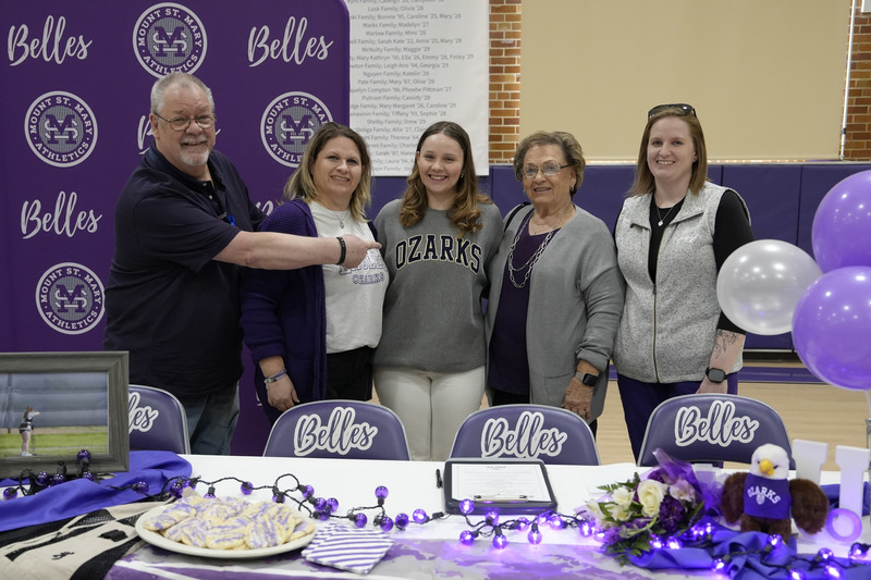 student and family members pose for photo at decorated table