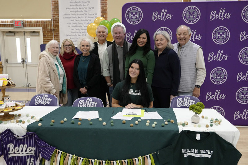 student and family members pose for photo at decorated table
