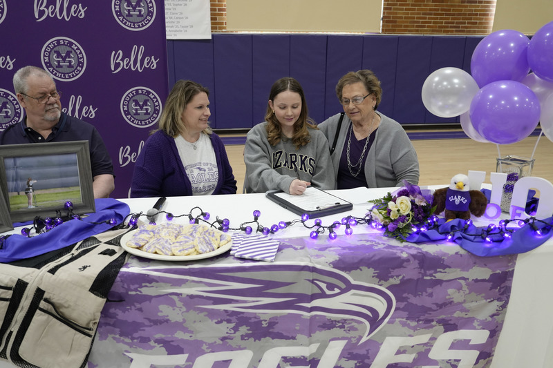 student signing letter of intent at decorated table alongside family members