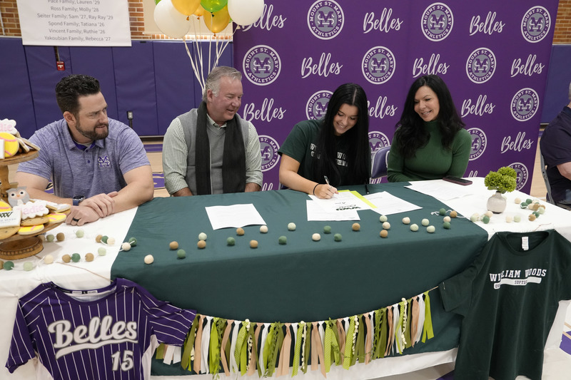 student signing letter of intent at decorated table alongside coach and parents