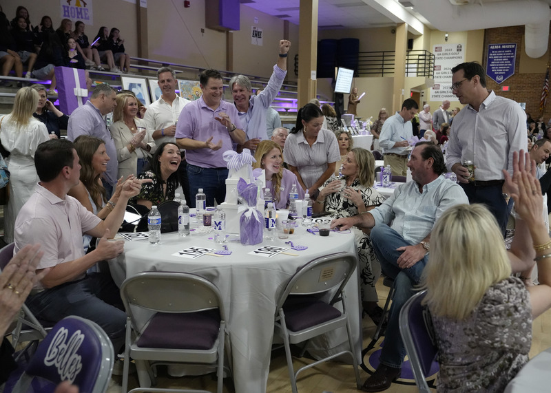 event guests celebrating  around a table after placing the winning bid in a live auction