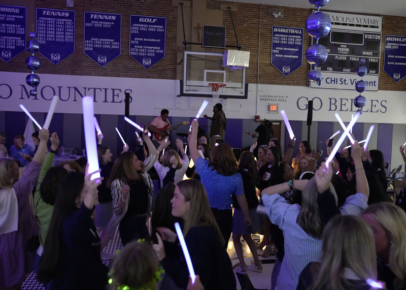 guests dancing at an event while waving glow sticks in the air