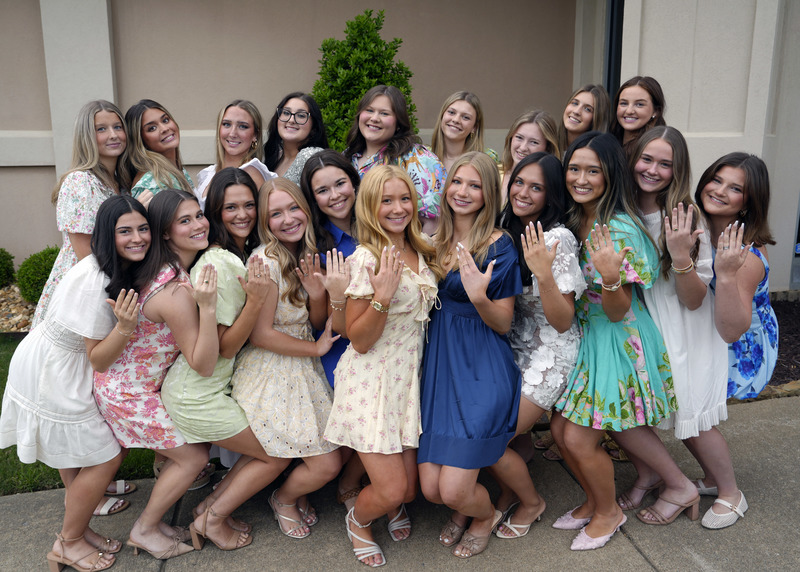 large group of girls smiling at camera and holding up hands to show newly received senior rings
