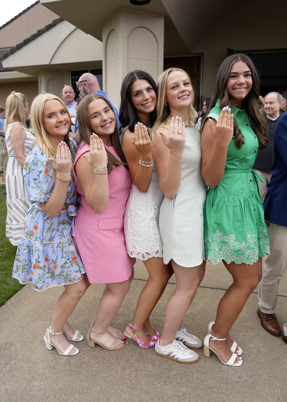 group of five girls smiling at camera and holding up hands to show newly received senior rings