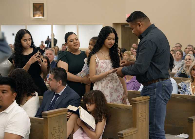 family members presenting student with senior ring during Mass inside a church