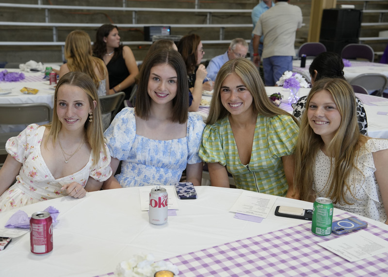 four students seated at a table enjoying a meal during a banquet