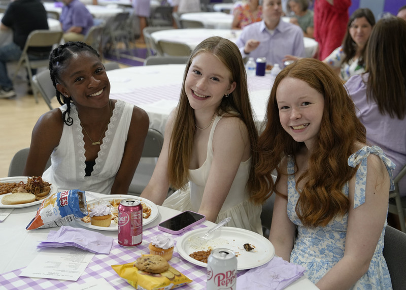 three students seated at a table enjoying a meal during a banquet