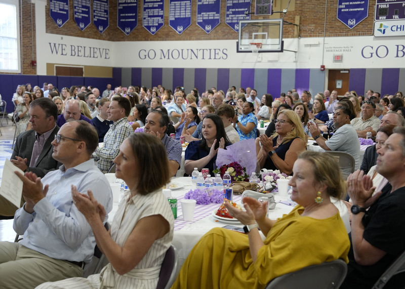 picture of crowd seated at during tables during a banquet and clapping