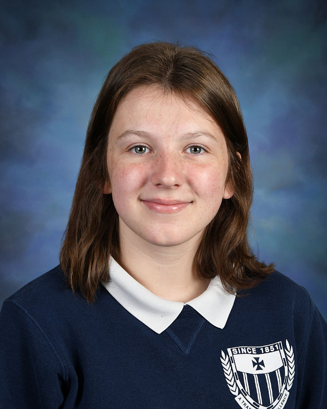 portrait image of female student in school uniform in front of blue background