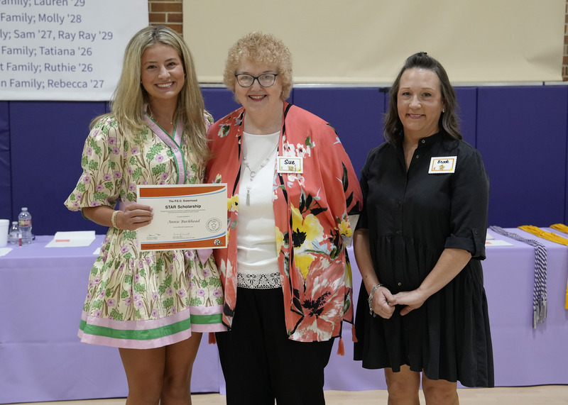 a student accepting an award certificate from two adults